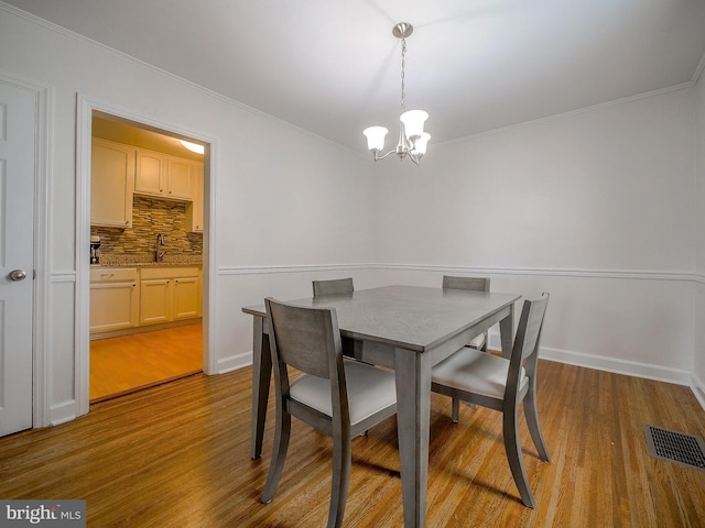 dining area featuring visible vents, wood finished floors, crown molding, and a chandelier