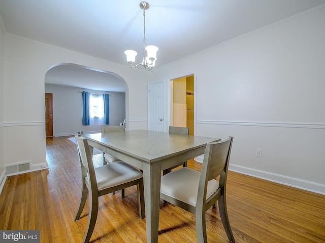 dining area with visible vents, a notable chandelier, wood finished floors, arched walkways, and baseboards