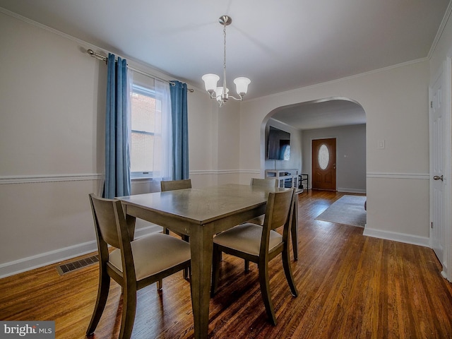 dining room with visible vents, baseboards, wood finished floors, arched walkways, and a notable chandelier