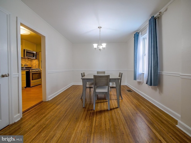 dining area featuring dark wood finished floors, visible vents, baseboards, and a chandelier