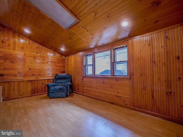 unfurnished room with light wood finished floors, baseboards, wood walls, lofted ceiling, and wooden ceiling