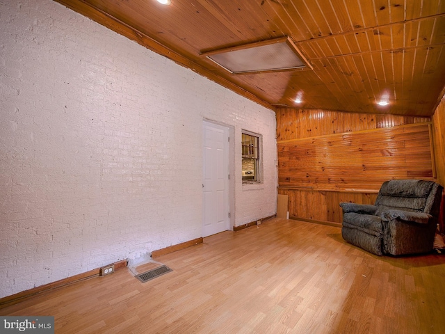 unfurnished room featuring visible vents, wood finished floors, brick wall, lofted ceiling, and wood ceiling