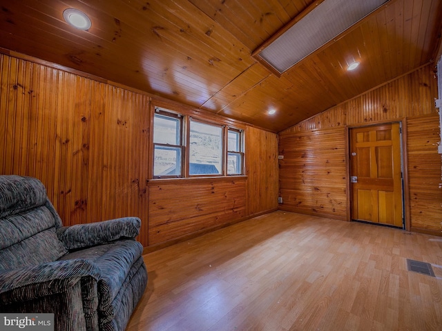 living area with visible vents, wood walls, wood ceiling, vaulted ceiling, and light wood-style floors