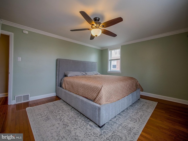 bedroom featuring visible vents, crown molding, baseboards, and wood finished floors