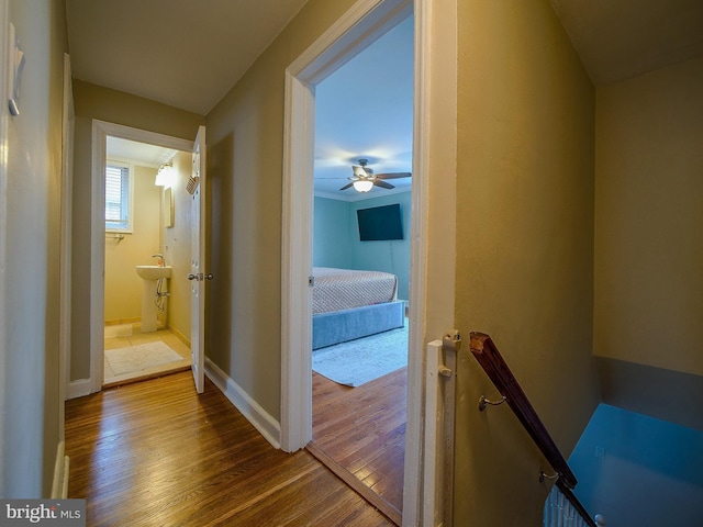 hallway with an upstairs landing, baseboards, and dark wood-style flooring