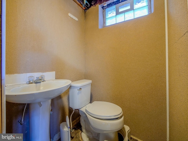 half bath featuring toilet and a textured wall