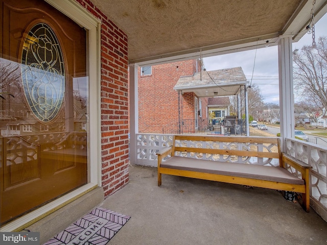 property entrance with brick siding and a porch