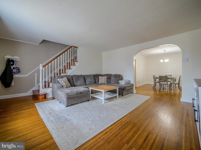 living area with baseboards, arched walkways, wood finished floors, and stairs