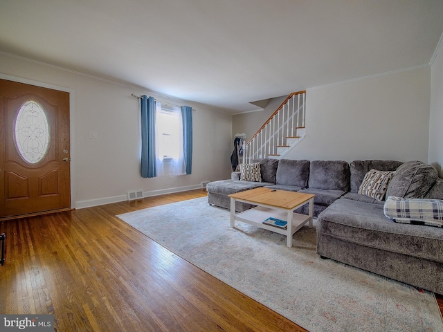 living room with visible vents, baseboards, stairs, ornamental molding, and hardwood / wood-style floors