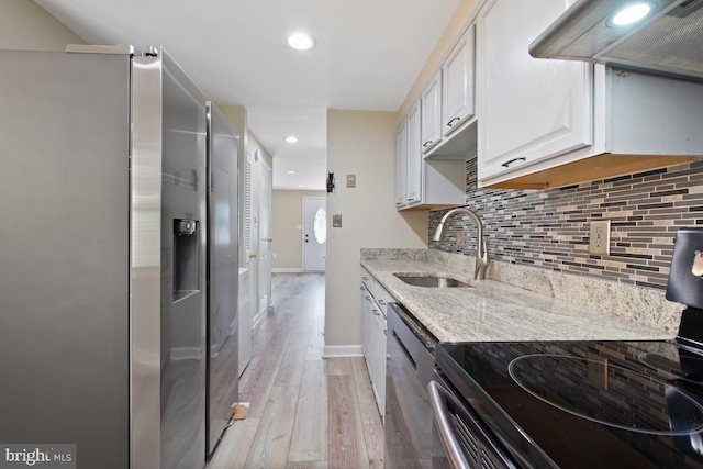 kitchen with light stone countertops, white cabinets, appliances with stainless steel finishes, light hardwood / wood-style floors, and ventilation hood