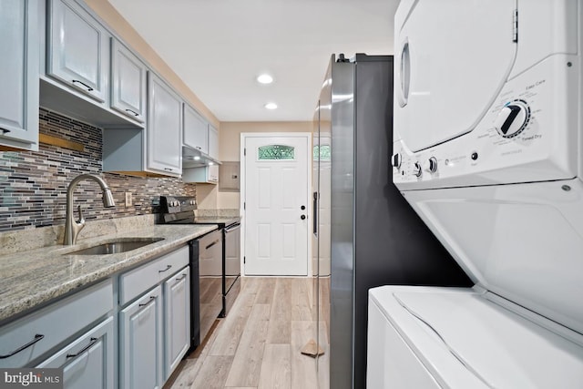 kitchen featuring stainless steel appliances, tasteful backsplash, light stone countertops, light hardwood / wood-style flooring, and sink