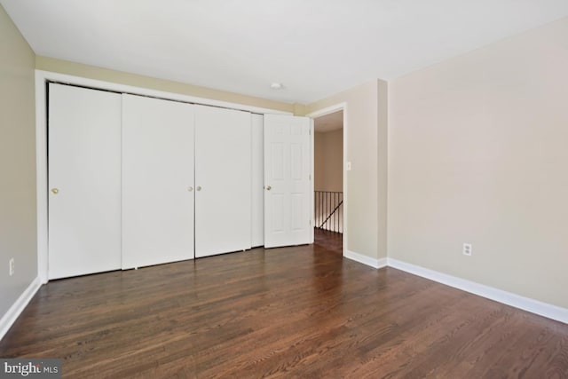 unfurnished bedroom with dark wood-type flooring and a closet