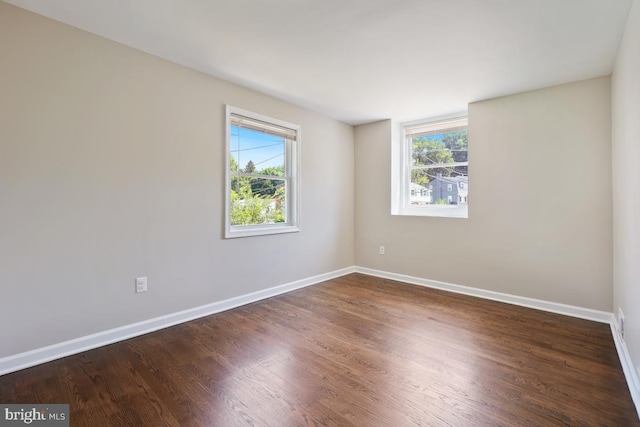 empty room with a healthy amount of sunlight and dark hardwood / wood-style floors