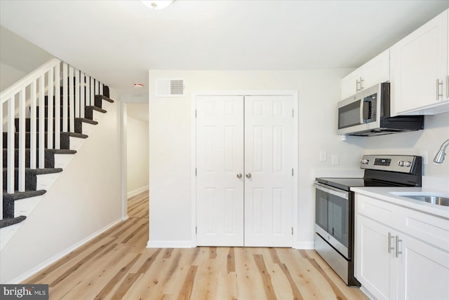 kitchen featuring white cabinets, light hardwood / wood-style floors, sink, and appliances with stainless steel finishes