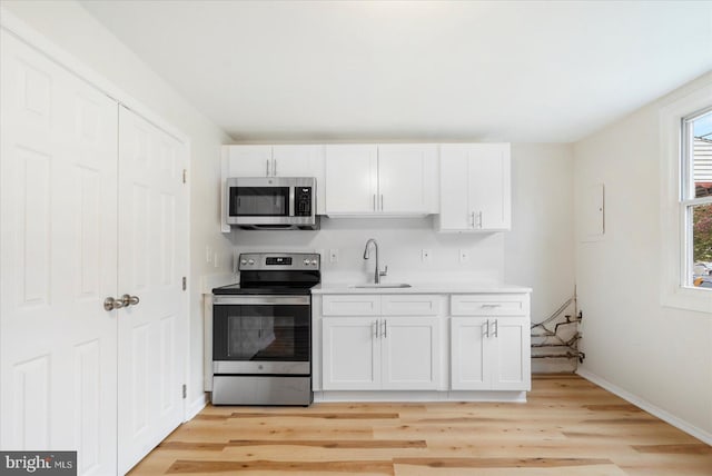 kitchen featuring white cabinetry, sink, light hardwood / wood-style floors, and appliances with stainless steel finishes