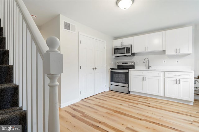 kitchen with sink, light wood-type flooring, white cabinetry, and stainless steel appliances