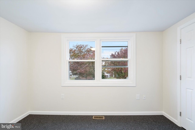 spare room with dark carpet