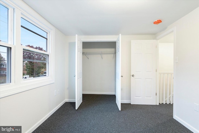 unfurnished bedroom with dark carpet and a closet