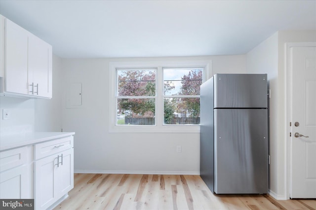 kitchen featuring white cabinets, stainless steel fridge, and light hardwood / wood-style flooring