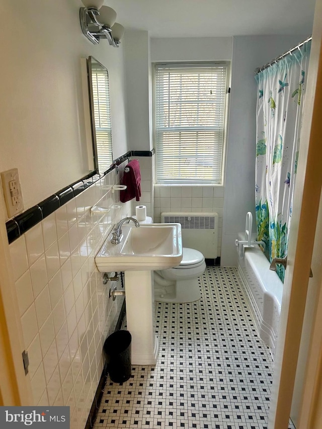 full bathroom with shower / tub combo, tile walls, tile patterned flooring, radiator heating unit, and toilet