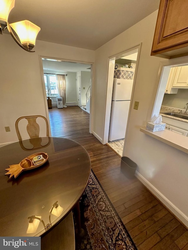 dining room with dark hardwood / wood-style floors, a baseboard heating unit, and sink