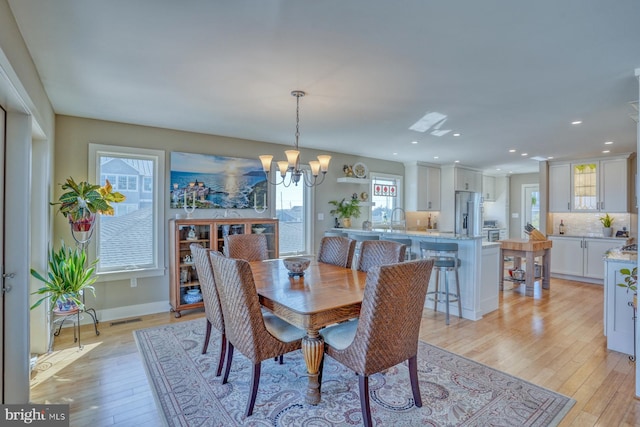 dining room with a chandelier, a wealth of natural light, sink, and light hardwood / wood-style floors