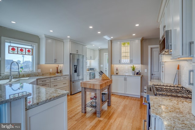 kitchen featuring light stone counters, white cabinetry, appliances with stainless steel finishes, and light hardwood / wood-style flooring