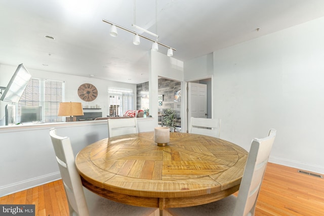 dining area with rail lighting and light hardwood / wood-style flooring