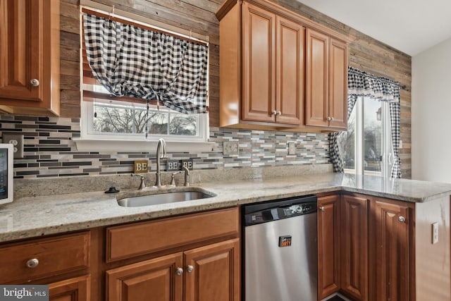 kitchen featuring stainless steel dishwasher, light stone counters, sink, and a wealth of natural light