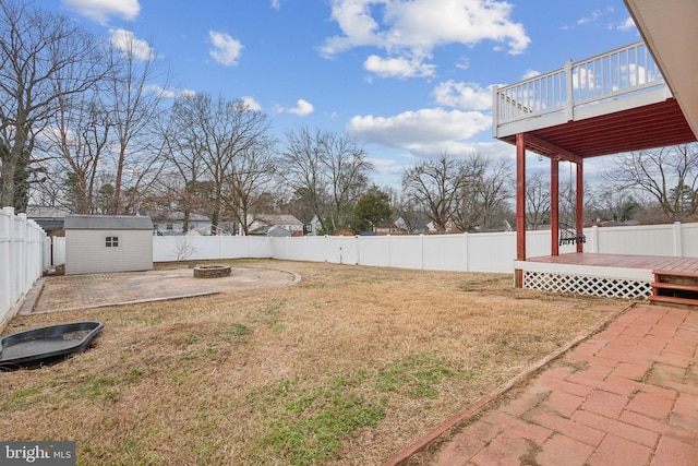 view of yard featuring a storage shed, a deck, and an outdoor fire pit