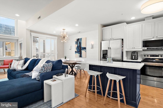 kitchen with a center island, stainless steel appliances, decorative light fixtures, a breakfast bar area, and white cabinets