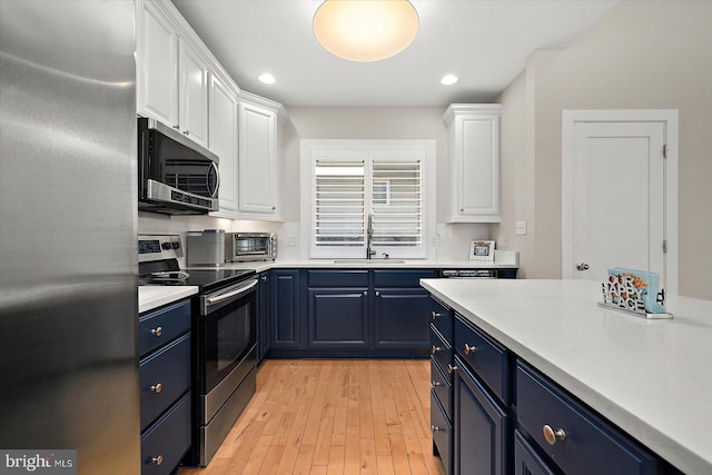 kitchen featuring white cabinetry, sink, stainless steel appliances, and blue cabinets