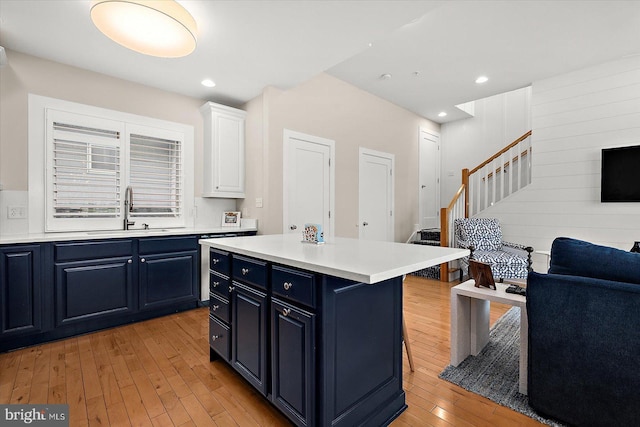 kitchen with a breakfast bar, blue cabinets, sink, white cabinets, and a center island