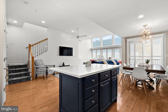 kitchen with hardwood / wood-style floors, a center island, and ceiling fan with notable chandelier