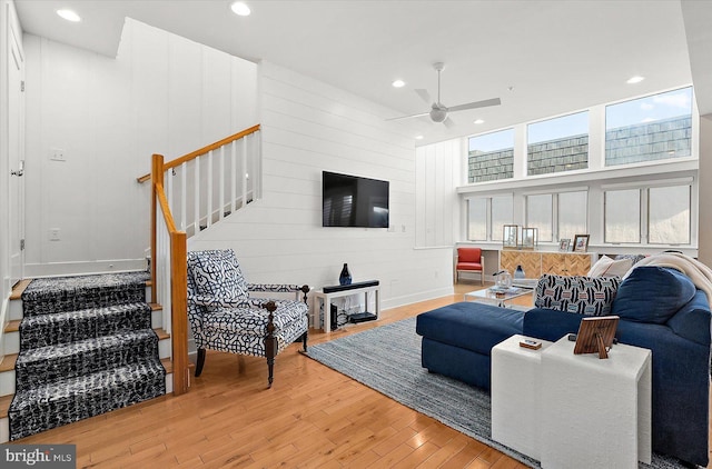 living room featuring wood-type flooring, ceiling fan, and a high ceiling