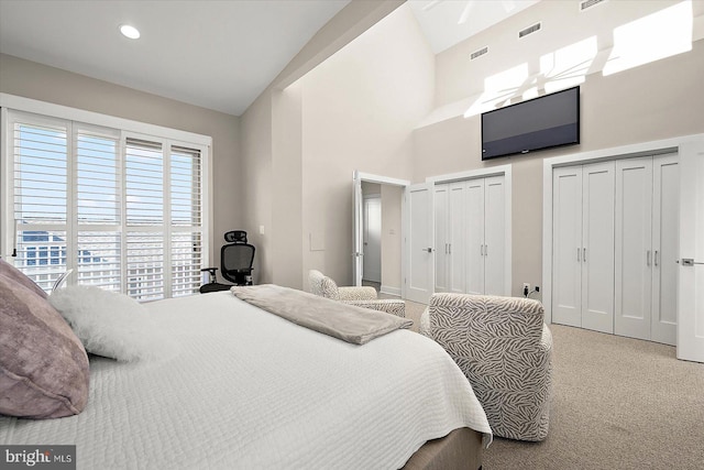 carpeted bedroom with high vaulted ceiling and two closets