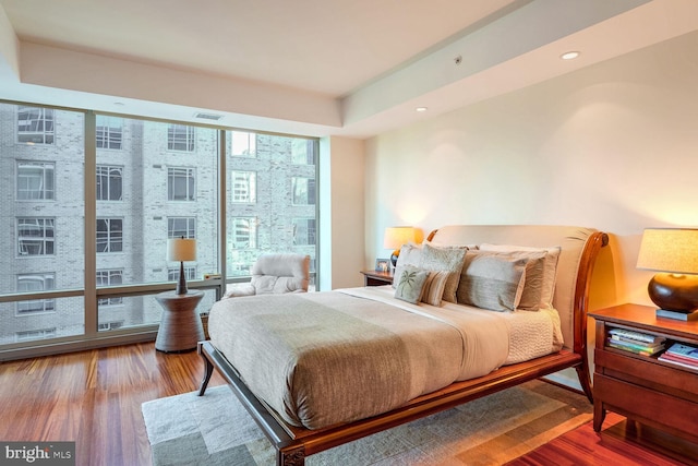 bedroom featuring wood-type flooring, floor to ceiling windows, and multiple windows