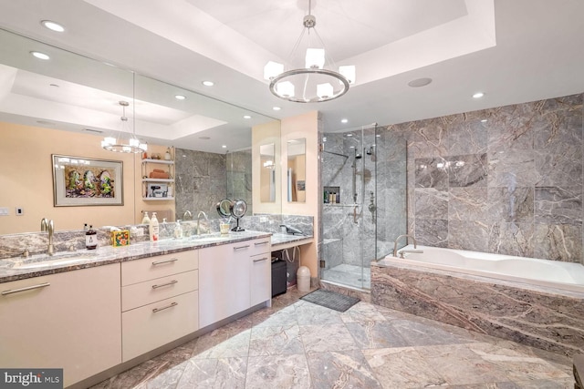 bathroom with a raised ceiling, shower with separate bathtub, vanity, and an inviting chandelier