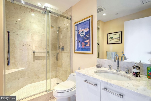 bathroom featuring vanity, a shower with shower door, and toilet