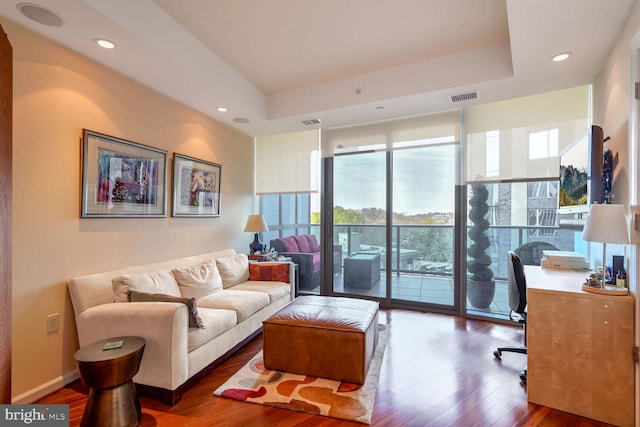 living room with floor to ceiling windows, dark wood-type flooring, and a tray ceiling