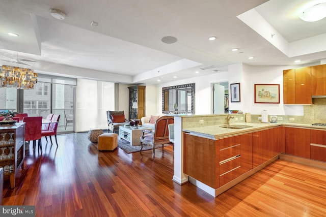 kitchen featuring hardwood / wood-style flooring, kitchen peninsula, sink, and backsplash