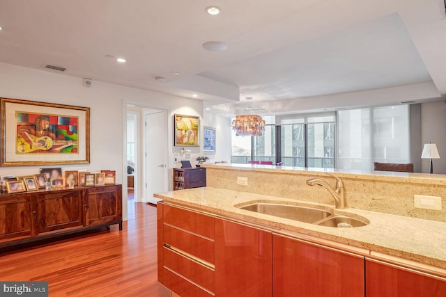 kitchen featuring light stone countertops, sink, and light wood-type flooring