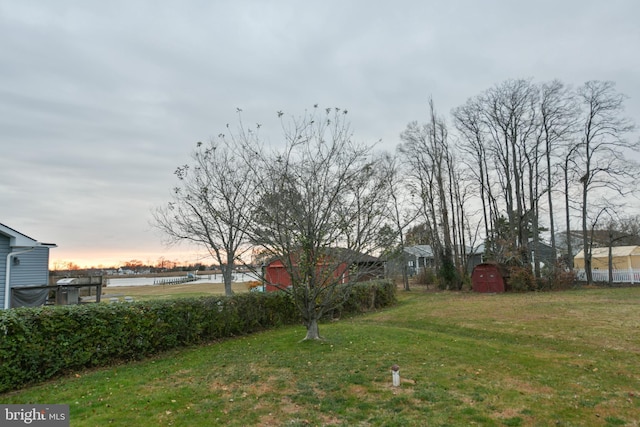 yard at dusk featuring a water view and a shed