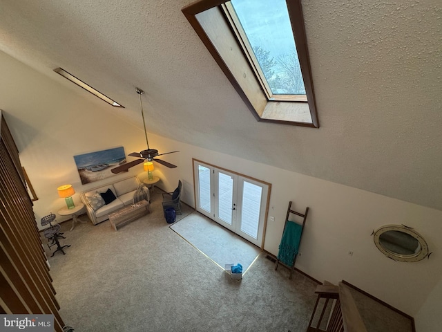 unfurnished living room featuring carpet flooring, french doors, a textured ceiling, lofted ceiling with skylight, and a healthy amount of sunlight