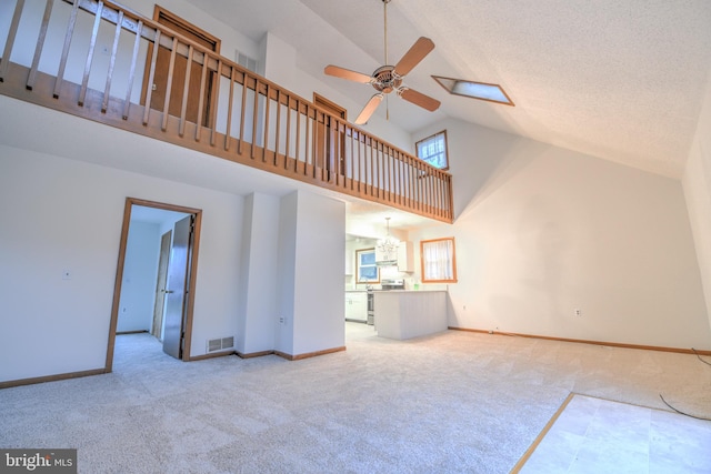 unfurnished living room featuring carpet, ceiling fan with notable chandelier, and plenty of natural light