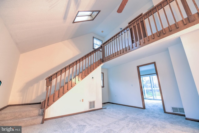 stairs featuring carpet and lofted ceiling with skylight