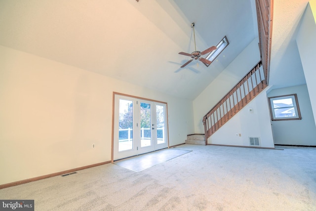 unfurnished living room with ceiling fan, carpet floors, high vaulted ceiling, and french doors