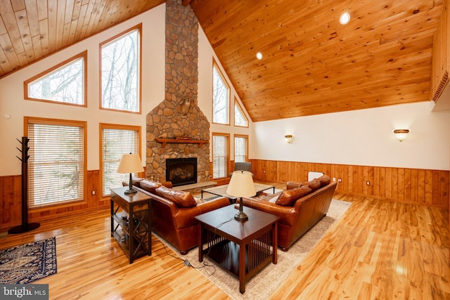 living room featuring wood ceiling, light wood-type flooring, a fireplace, and a wealth of natural light