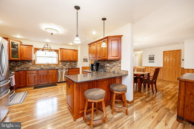 kitchen featuring kitchen peninsula, sink, appliances with stainless steel finishes, and light hardwood / wood-style flooring