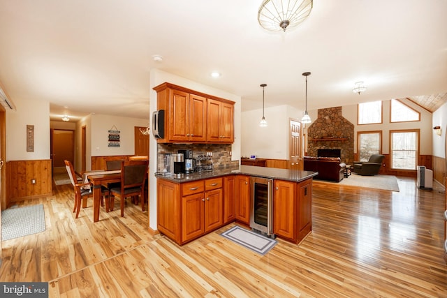 kitchen with wooden walls, a stone fireplace, light wood-type flooring, and wine cooler